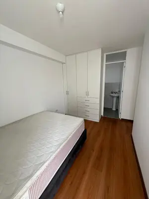 a bedroom with a white bed and a wooden floor at Departamento San Sebastian in Lima