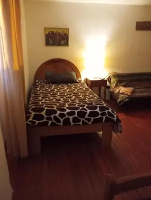a bedroom with a bed with a black and white comforter at Gatanas House in Cusco