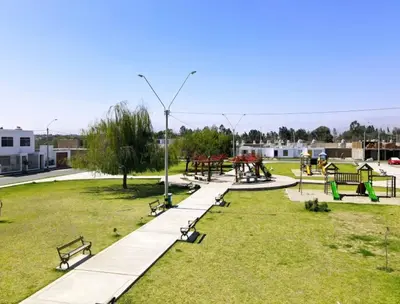 a park with benches and picnic tables in the grass at Ethan's House - Como en Casa