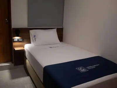 a hotel room with a bed with a blue and white pillow at Luxotel Business Chincha in Chincha Alta
