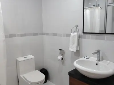 a white bathroom with a toilet and a sink at Luxotel Business Chincha in Chincha Alta
