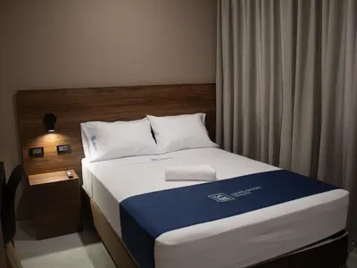 a bedroom with a bed with a blue and white blanket at Luxotel Business Chincha in Chincha Alta