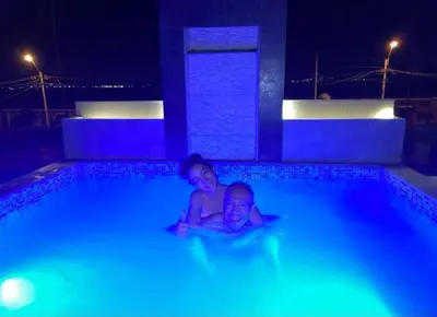 two children laying in a swimming pool at night at Casa con piscina, terraza y parrilla en Ica in Ica