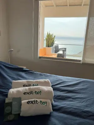 a bedroom with towels on a bed with a window at Condominio Maradentro - Casas de playa en exclusivo balneareo de chepeconde in Los Leones