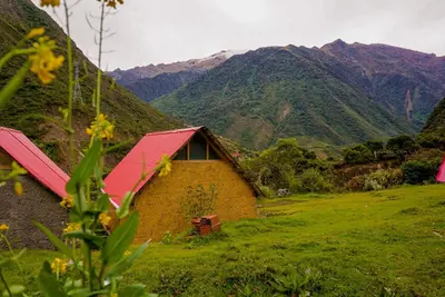 a house in a field with mountains in the background at Yawar inka ayllu challhuay in Colcapampa