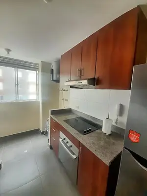 a kitchen with wooden cabinets and a stove top oven at Departamento con Vista al Mar in Lima