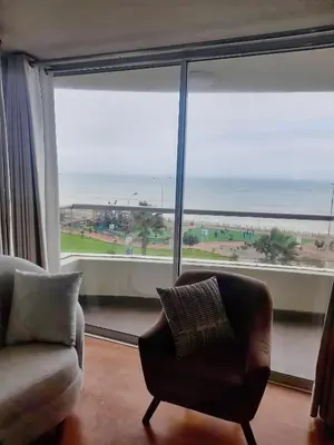 a living room with a chair and a view of the ocean at Departamento con Vista al Mar in Lima