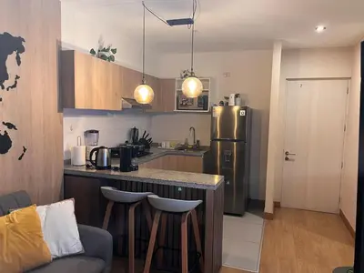 a kitchen with a refrigerator and a counter with stools at Tempo Moderno Departamento in San Antonio