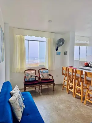 a living room with a blue couch and a table with chairs at Departamento en Chancay con Vista al Mar y cerca al Megapuerto