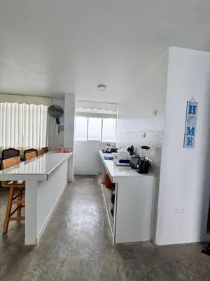 a kitchen with white counters and a table in it at Departamento en Chancay con Vista al Mar y cerca al Megapuerto