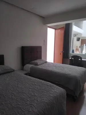 a hotel room with two beds and a window at Hotel Rodilla in Ayacucho