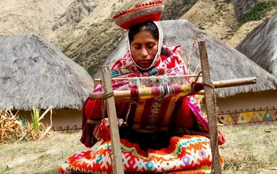 a woman is sitting down holding a stick at hotel turismo vivencial pallay lliclla in Urubamba