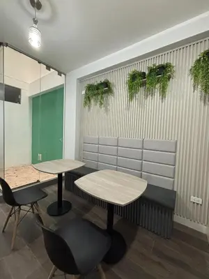 two tables and chairs in a room with plants on the wall at Hospedaje Bry Ker in Pichanaki