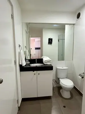 a white bathroom with a toilet and a sink at Departamento Lock in Lima