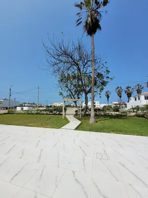 a tile walkway with a palm tree in the background at Casa con Piscina privada y a pasos de la playa in Lurín