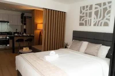 a bedroom with a large white bed and a kitchen at Patria Inca Inn in Lima