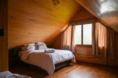 a bedroom with a bed in a wooden cabin at Montecatini Ecolodge in Oxapampa