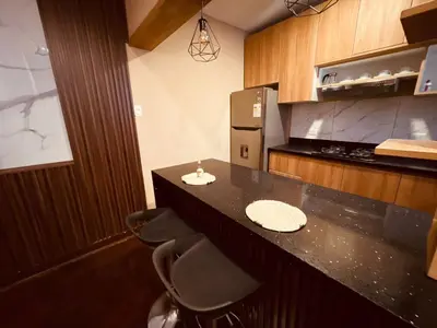 a kitchen with a counter with stools and a refrigerator at Céntrico Dpto Puca Lima a 2 cuadras de Hospital Rebagliati y Real Plaza Salaverry in Lima