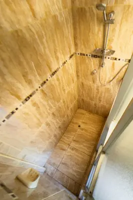 a shower in a bathroom with a wooden ceiling at Pinkuylluna Lodge in Ollantaytambo