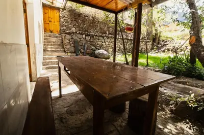 a wooden bench sitting on the porch of a house at Pinkuylluna Lodge in Ollantaytambo