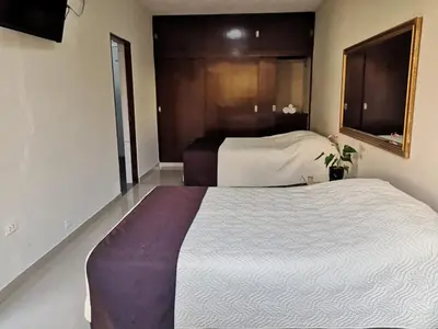 a hotel room with two beds and a window at Casa Grau Chincha in Chincha