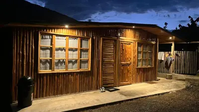 a wooden house with a door and windows at night at CABAÑAS RANCH OXaPAMP4 in Oxapampa
