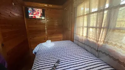 a bedroom with a bed and a tv and a window at CABAÑAS RANCH OXaPAMP4 in Oxapampa