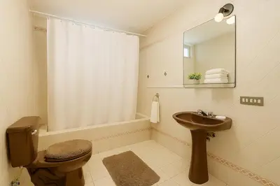 a bathroom with a sink and a toilet and a mirror at Lima Family Lodge Apartment near Miraflores Center in Lima