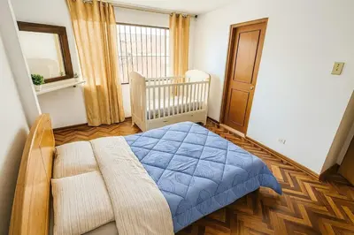 a bedroom with a blue bed and a crib at Lima Family Lodge Apartment near Miraflores Center in Lima