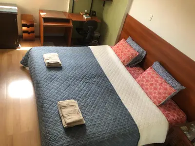 a bedroom with a bed with pillows and a desk at Departamento familiar Lucrepata in Cusco