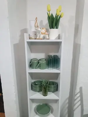 a white shelf with green dishes and flowers on it at IN FRONT OF THE NEW AIRPORT Hospedaje - A y C Taxi Free - Airport - Apartment on the 1st Floor in Lima