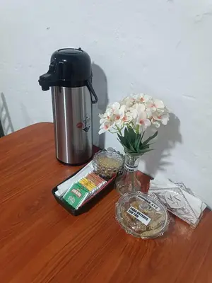 a table with a coffee maker and a vase of flowers at IN FRONT OF THE NEW AIRPORT Hospedaje - A y C Taxi Free - Airport - Apartment on the 1st Floor in Lima