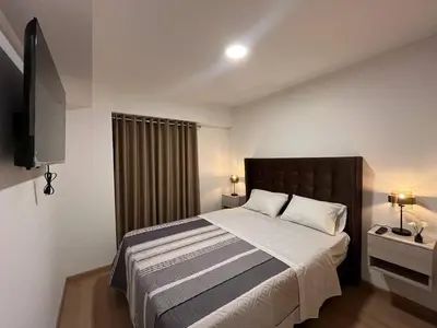a bedroom with a large bed and a television at Apartamento Amoblado a un paso del parque de las aguas in Lima