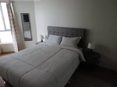 a bedroom with a large bed with white sheets and pillows at Panoramic View in Lima