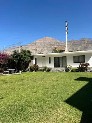 a white house with a grassy yard in front of it at La Casita de Condoray - Lunahuana in Lunahuaná