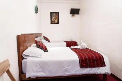 two beds in a room with white walls at HOTEL PALACE DIAZ inn in Cusco