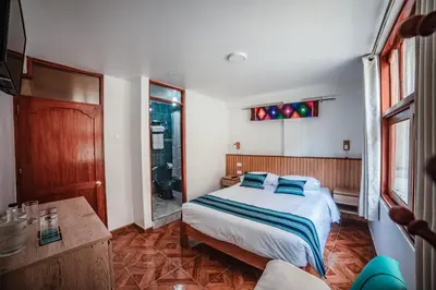 a bedroom with a bed with blue pillows at Casa Andora in Machu Picchu