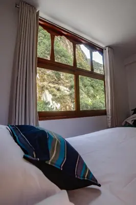 a bedroom with a window and a bed with a pillow at Casa Andora in Machu Picchu