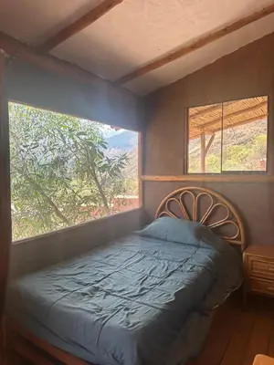 a bedroom with a bed and two windows at Casa Divina Medicina in Urubamba