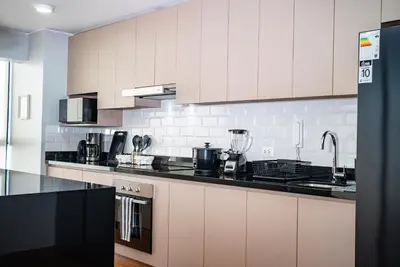 a kitchen with white cabinets and black counter tops at Duplex Moderno y Espacioso en Miraflores in Lima