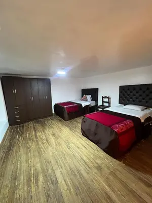 a hotel room with two beds and wooden floors at Redy's House in Cusco
