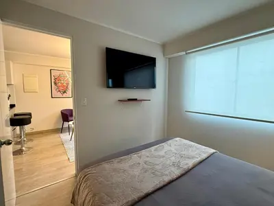 a bedroom with a bed and a flat screen tv at Departamento Osma in Lima