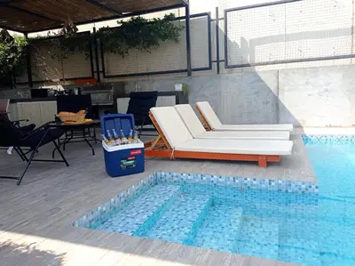 a pool with a couch and a chair next to a swimming pool at Maya House Cieneguilla in Cieneguilla