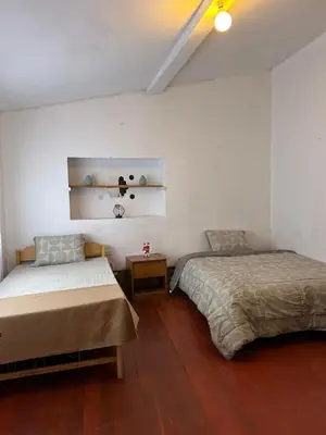 two beds in a room with white walls and wooden floors at Valentino Vent in Cusco