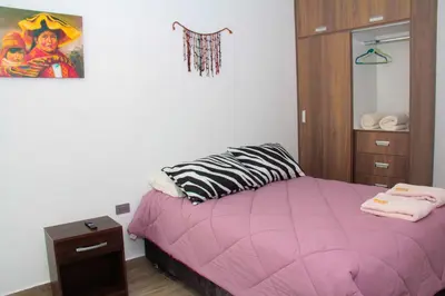 a bedroom with a pink bed and a cabinet at Valle Sagrado Mágico in Urubamba