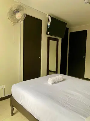 a bedroom with a white bed with a fan at Hotel Naciones Unidas in Lima