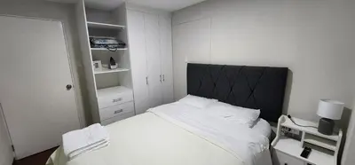 a bedroom with a white bed with a black headboard at Modern suite in San Miguel -Costa 21 in Lima