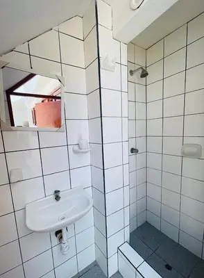 a white tiled bathroom with a sink and a mirror at Casa de Playa en Lobos in Cerro Azul