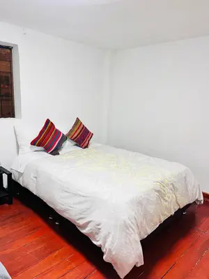 a white bed with two pillows on top of it at SkyGuest Cusco San Cristobal in Cusco