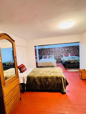 a bedroom with two beds and a mirror at SkyGuest Cusco San Cristobal in Cusco